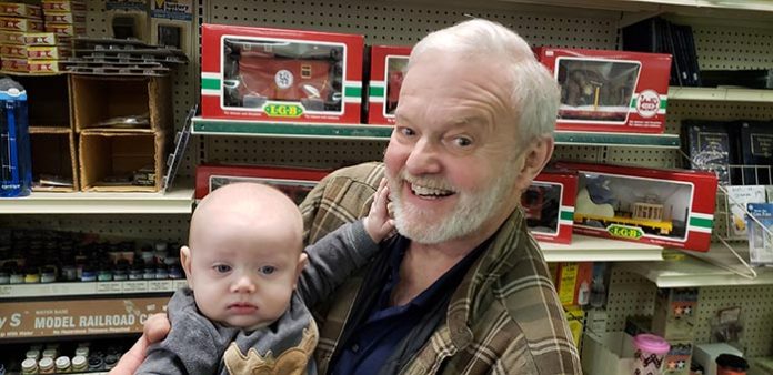 Frank Gustafson holds his 6-month-old grandson Grayson Weiss, who came for a visit during the last day of operation of his grandfather's store, the Jackson Hobby Shop. (Photo by Bob Vosseller)