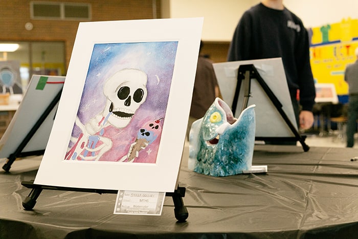 “An ice-cream-cone-eating skeleton and a fish” was an odd coupling at the fine art display in the cafeteria. Sierra Gregory created the watercolor of the skeleton, and Alexis Jackson created the fish ceramic. (Photo by Jennifer Peacock)