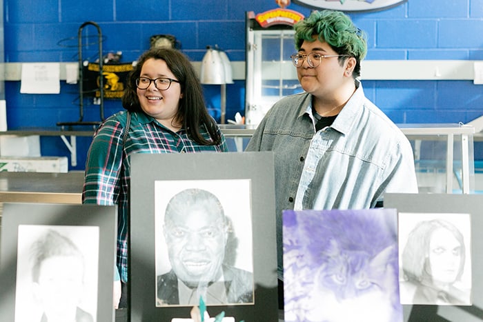 Senior Arceli Yutuc, right, and an identified friend stand by Yutuc’s table featuring her artwork. (Photo by Jennifer Peacock)