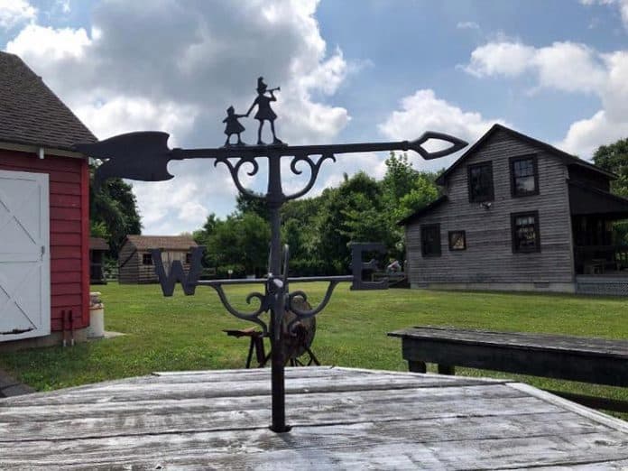 Weathervane temporarily on table with barn on left and Lizzie Herbert Gift Shop on right at Havens Homestead Museum property, 521 Herbertsville Rd., Brick. (Photo courtesy Brick Historical Society)